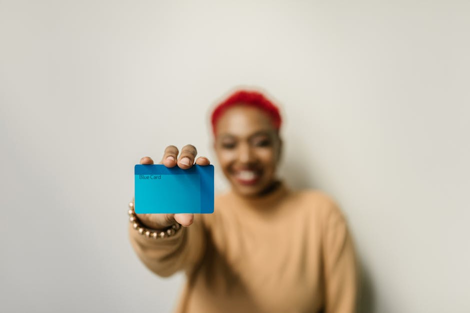 A cheerful woman with red hair displays a blue card against a neutral background, focused on the card.