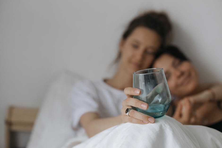 A loving couple sharing a tranquil moment indoors, holding a glass.