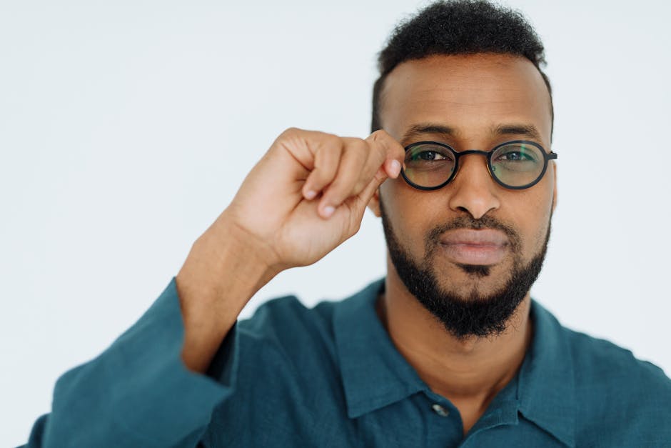 Portrait of a confident man wearing glasses and a blue shirt on a white background.