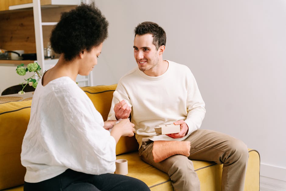 A happy couple sitting on a yellow sofa enjoying each other's company at home.