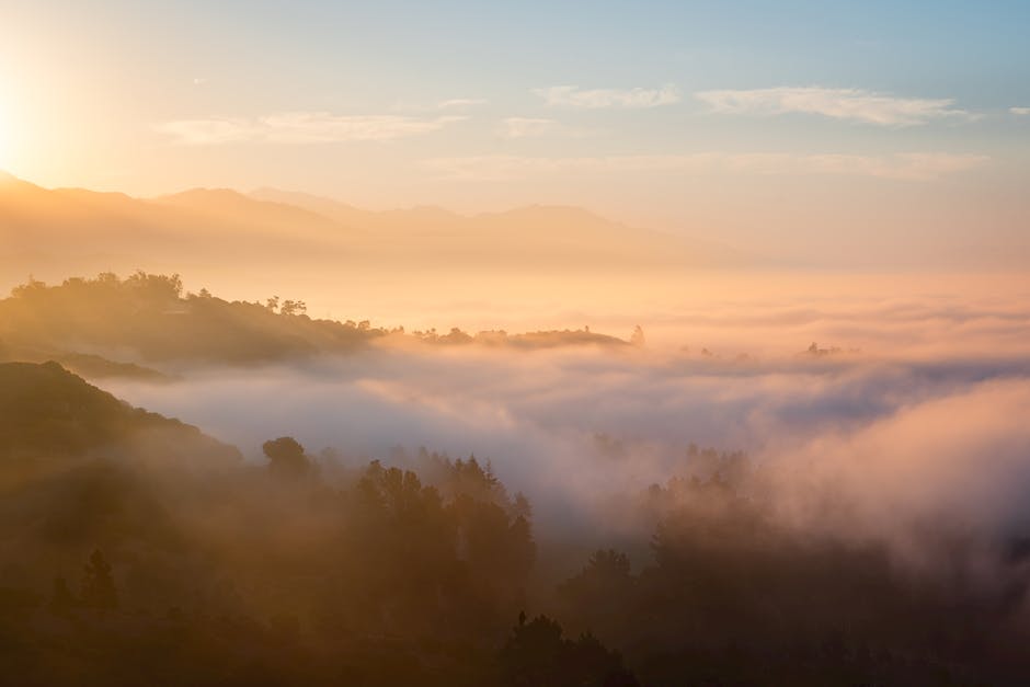 A captivating sunrise over misty hills with ethereal fog and serene light.