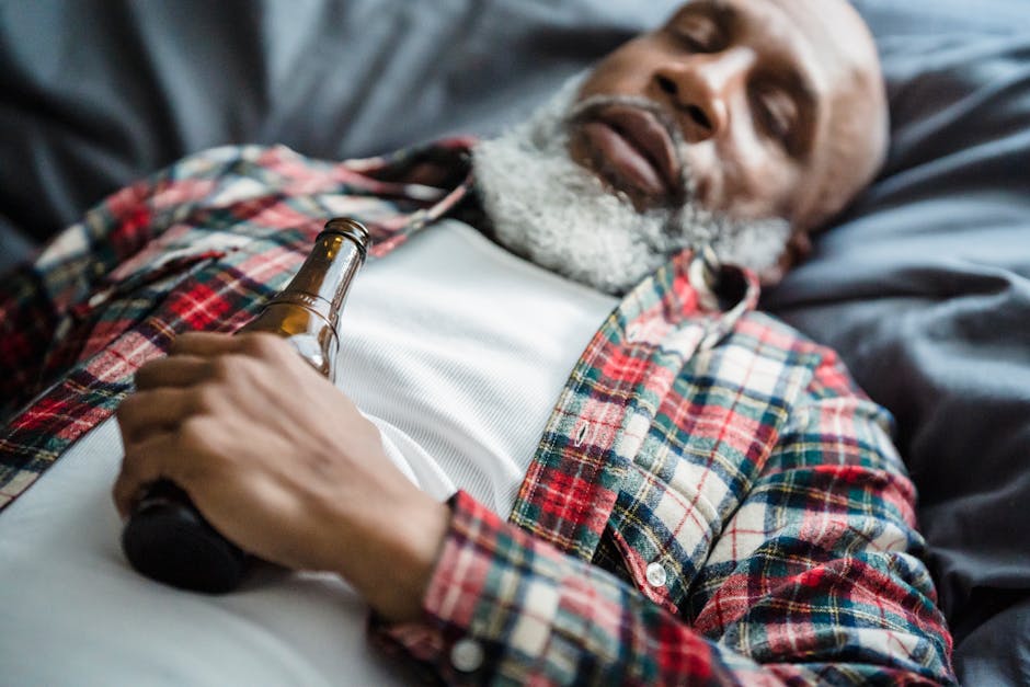 Close-up of a relaxed man lying down with a beer bottle, resting indoors.