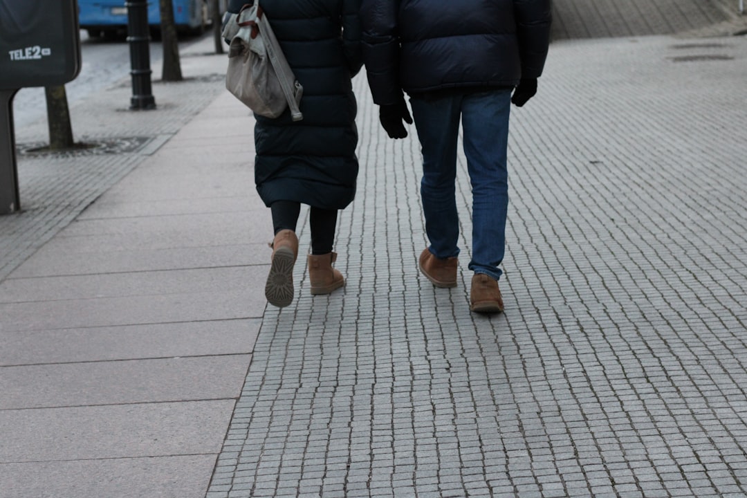 Two people walking down a sidewalk holding umbrellas