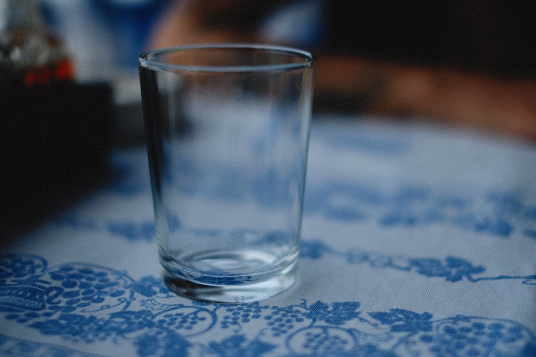 a shot glass sitting on a table with a person in the background