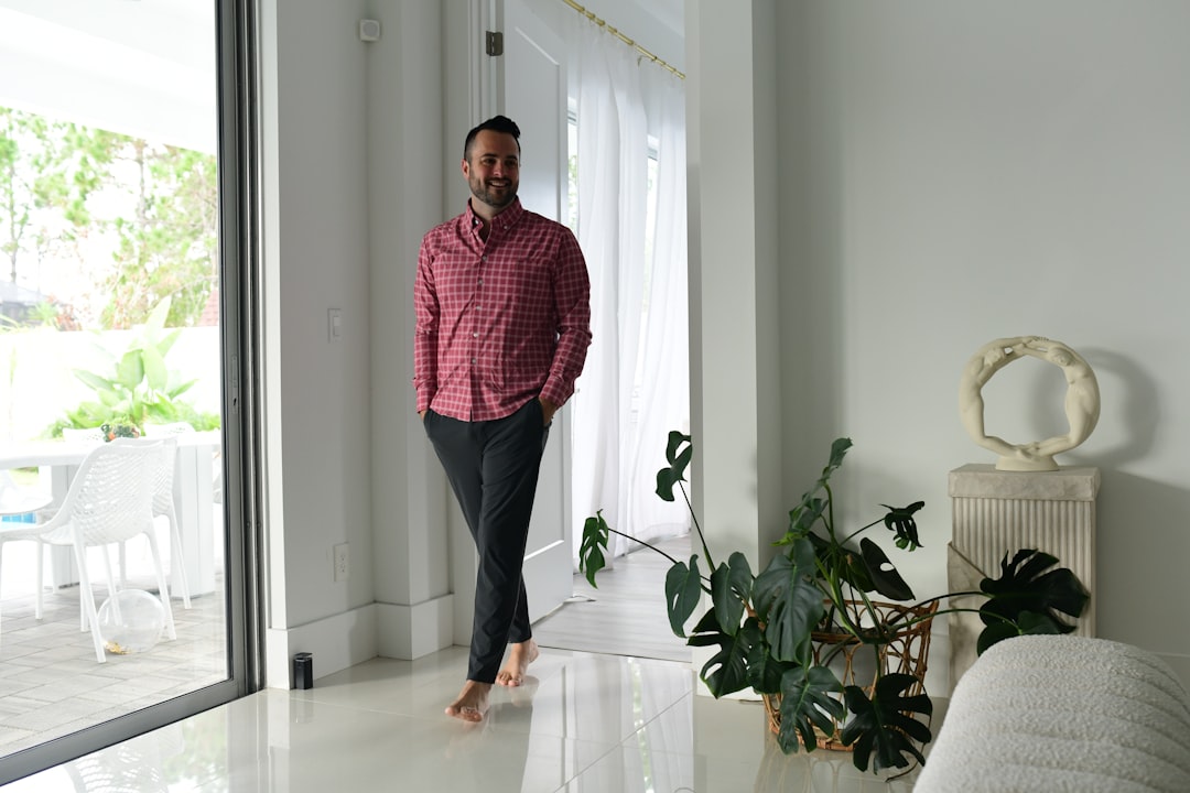 a man standing in a living room next to a plant