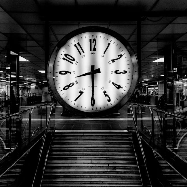 Monochrome image of a large clock at a train station, conveying the passage of time.