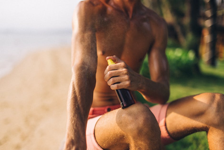 Close-up of a man applying tanning spray on a sunny beach day.