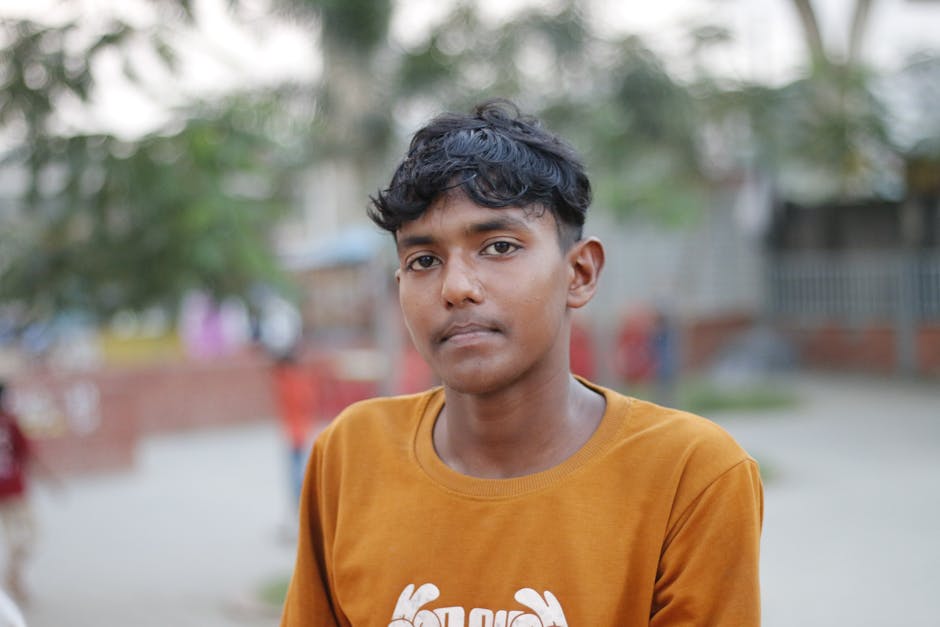 Young man in casual attire outdoors, looking thoughtfully at the camera.