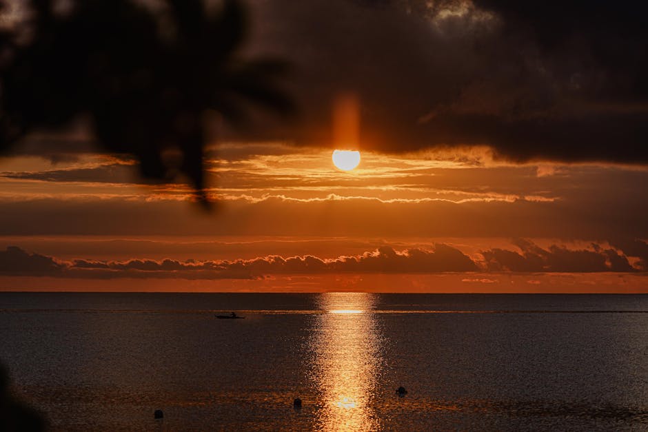 A serene sunset over the ocean with dramatic clouds and a tranquil atmosphere.